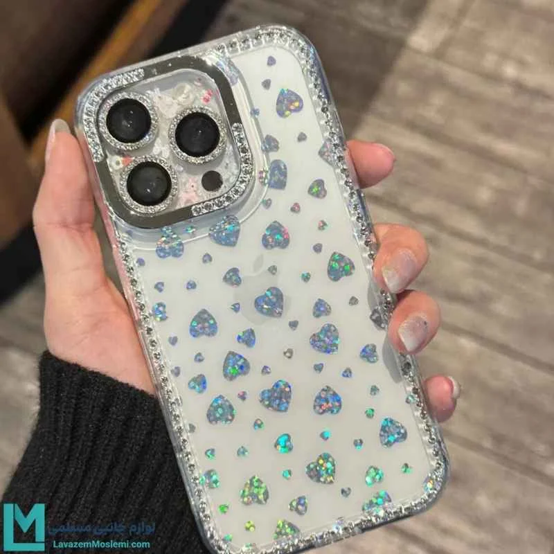 قاب گوشی شفاف با طرح قلب هلوگرامی و دور نگین دار مدل C1818 در دست با درخشش نور.